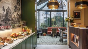 A modern kitchen with a breakfast bar, green cabinets, and a view of the garden through large windows. - Hôtel Littéraire Stendhal et Spa (Nancy)