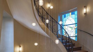 A spiral staircase with a wrought iron railing and hanging light fixtures. - Hôtel Littéraire Stendhal et Spa (Nancy)