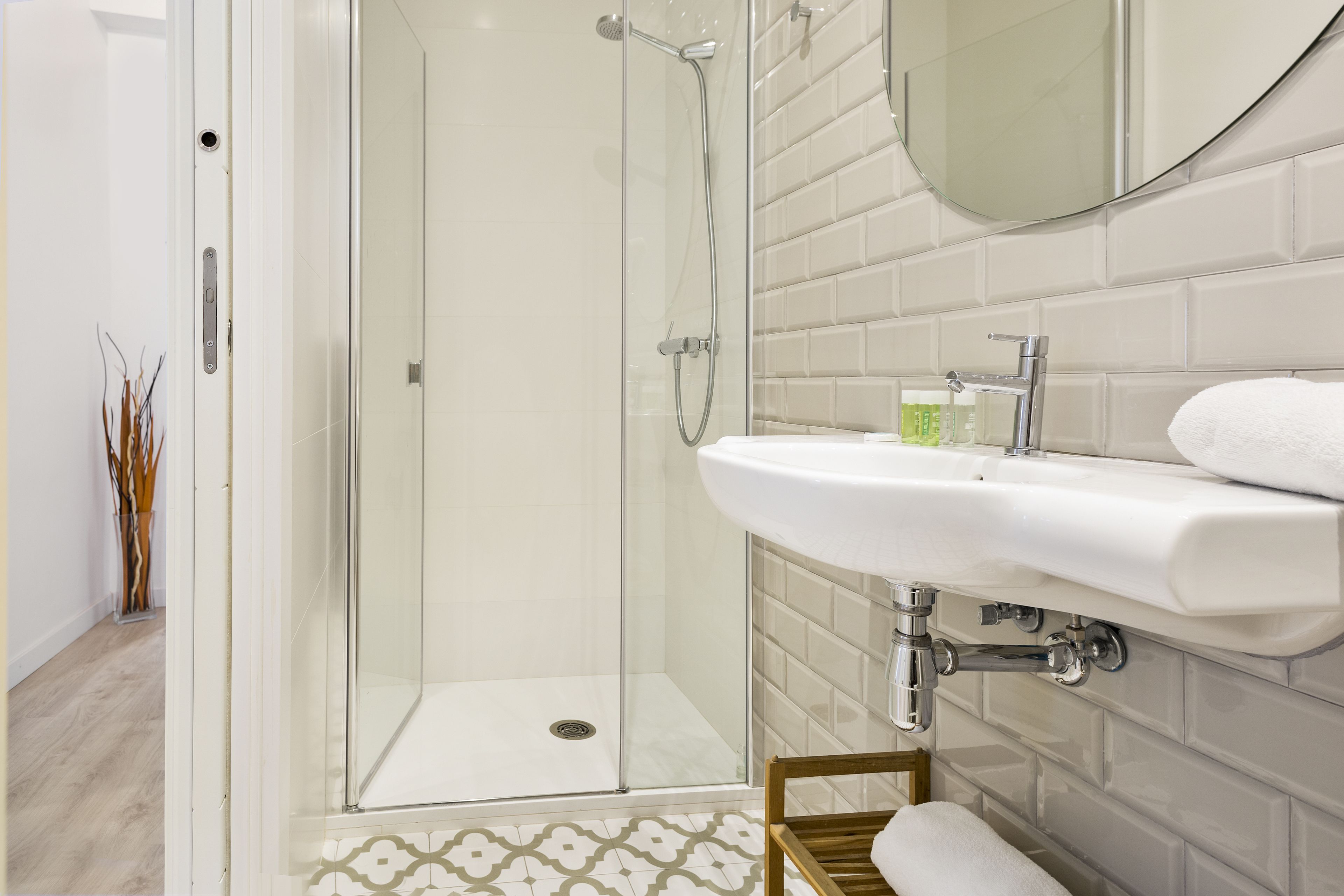 A modern bathroom with a glass-enclosed shower, a white sink, and a mirror.