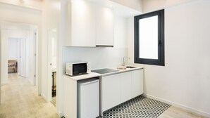 A compact kitchen with white cabinets, a microwave, and a sink. - BcnStop Parc Güell (Barcelona)
