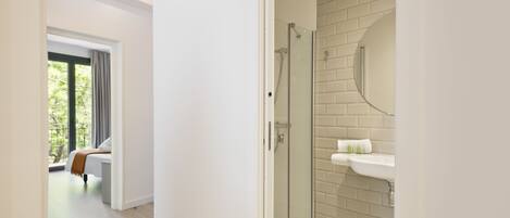 A modern bathroom with a glass shower enclosure, a white sink, and a tiled floor.