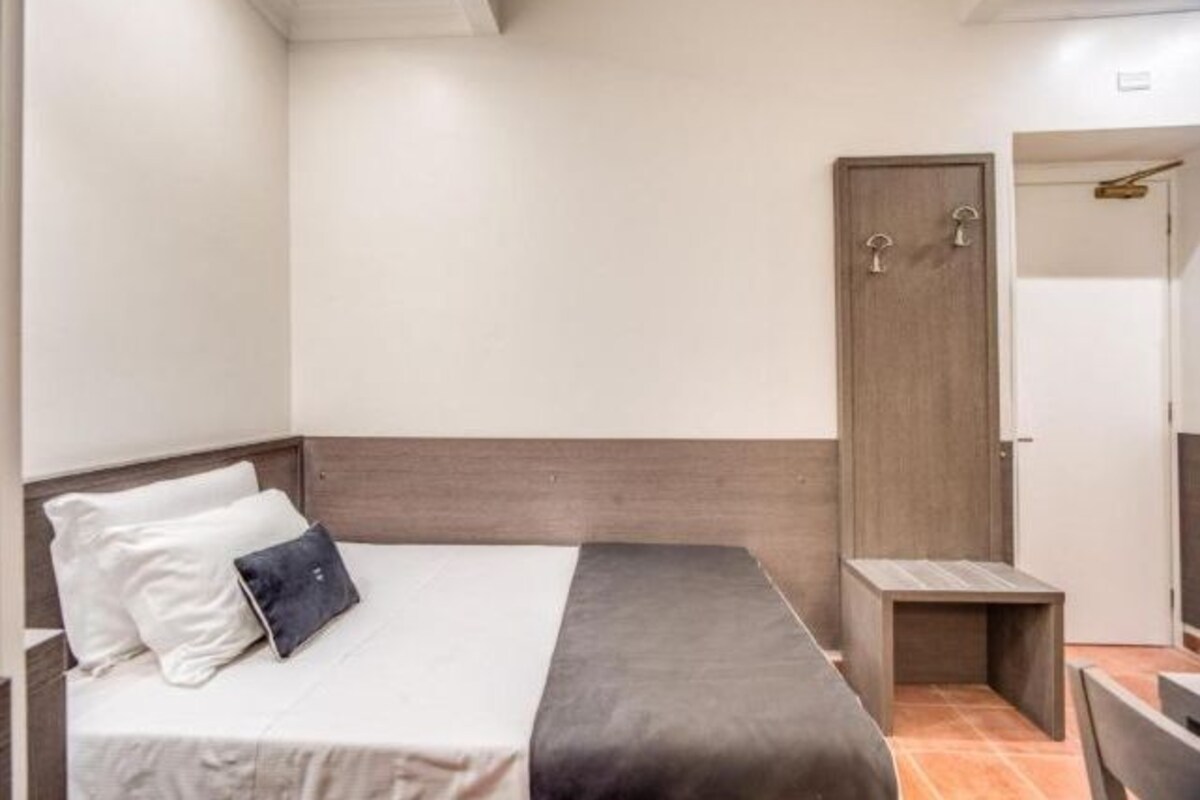 A neatly arranged bedroom with a bed, bedside table, and a door.