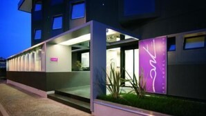 A modern hotel entrance with a glass facade, a well-lit reception area, and a visible outdoor garden. - Art Hotel Udine (Udine)