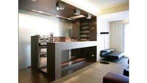 A modern kitchen with built-in appliances, a seating area with a sofa, and a bookshelf. - Art Hotel Udine (Udine)