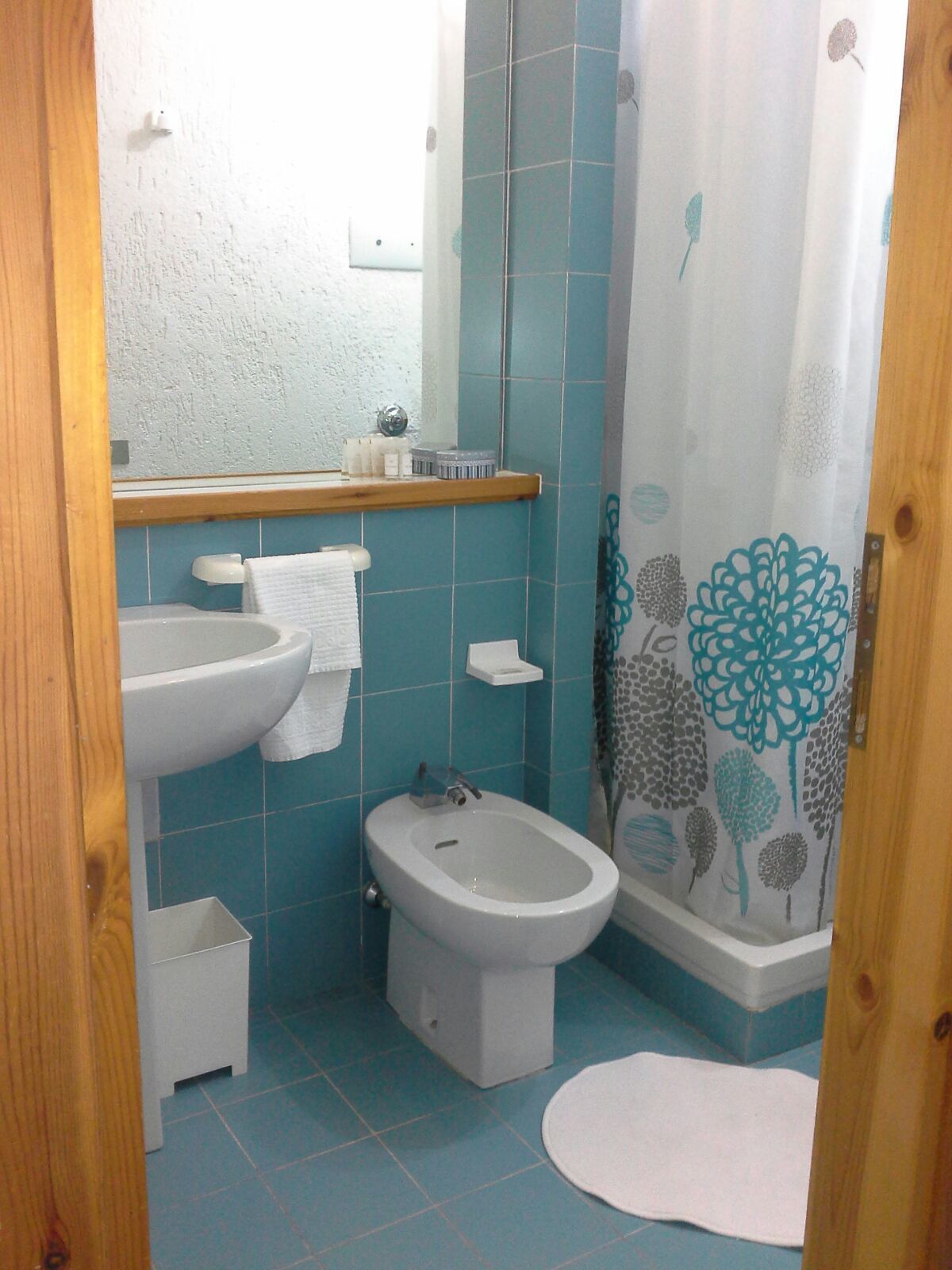 Un baño con bidé, lavamanos y espejo.