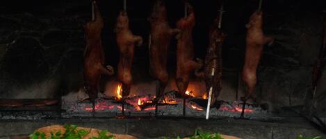 A traditional roasting spit with several whole pigs being cooked over an open fire.