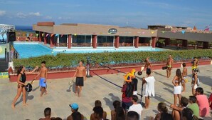 Zona junto a la piscina con espacio para espectadores, un escenario y un edificio con un letrero.