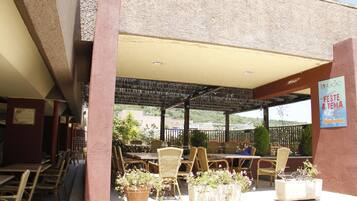 Un café al aire libre con mobiliario de mimbre y plantas en macetas.