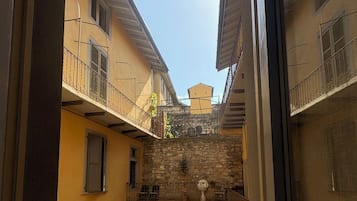 Ein Innenhof mit einer Steinmauer, einem kleinen Garten und einem Gebäude mit einem Balkon.