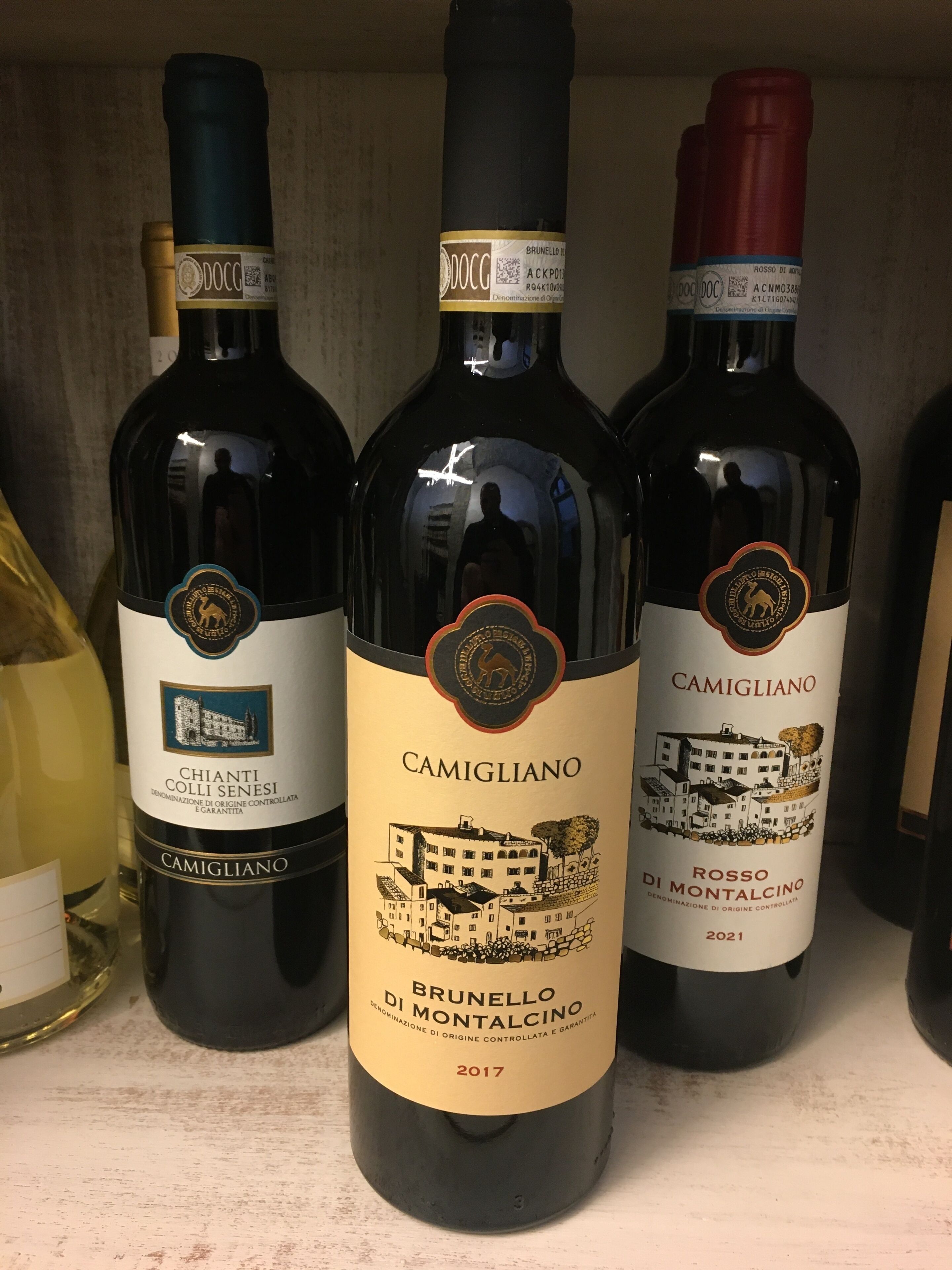 Three bottles of wine on a shelf.