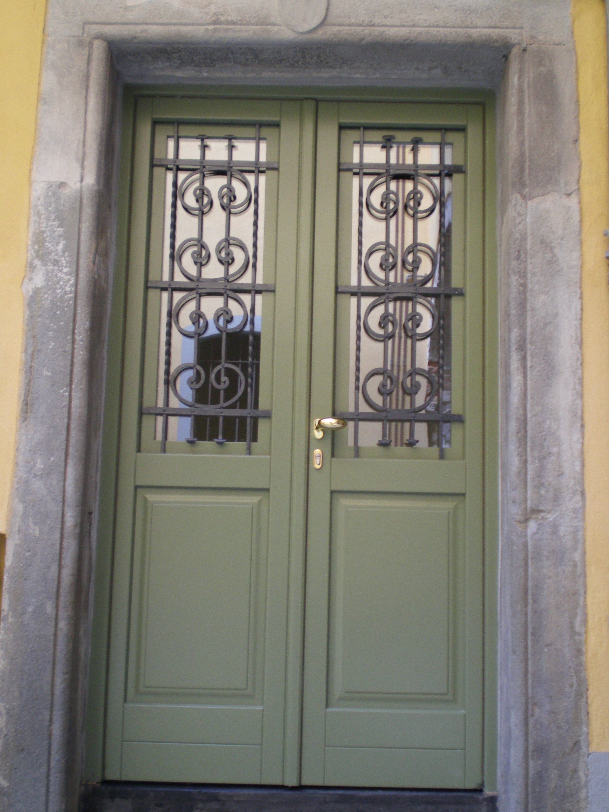 A green door with a metal gate and a brass handle.