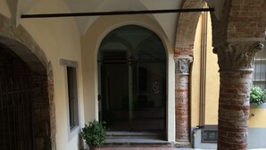 A courtyard with a brick floor, an arched doorway, and a potted plant. - Casa Mario Lupo (Bergamo)
