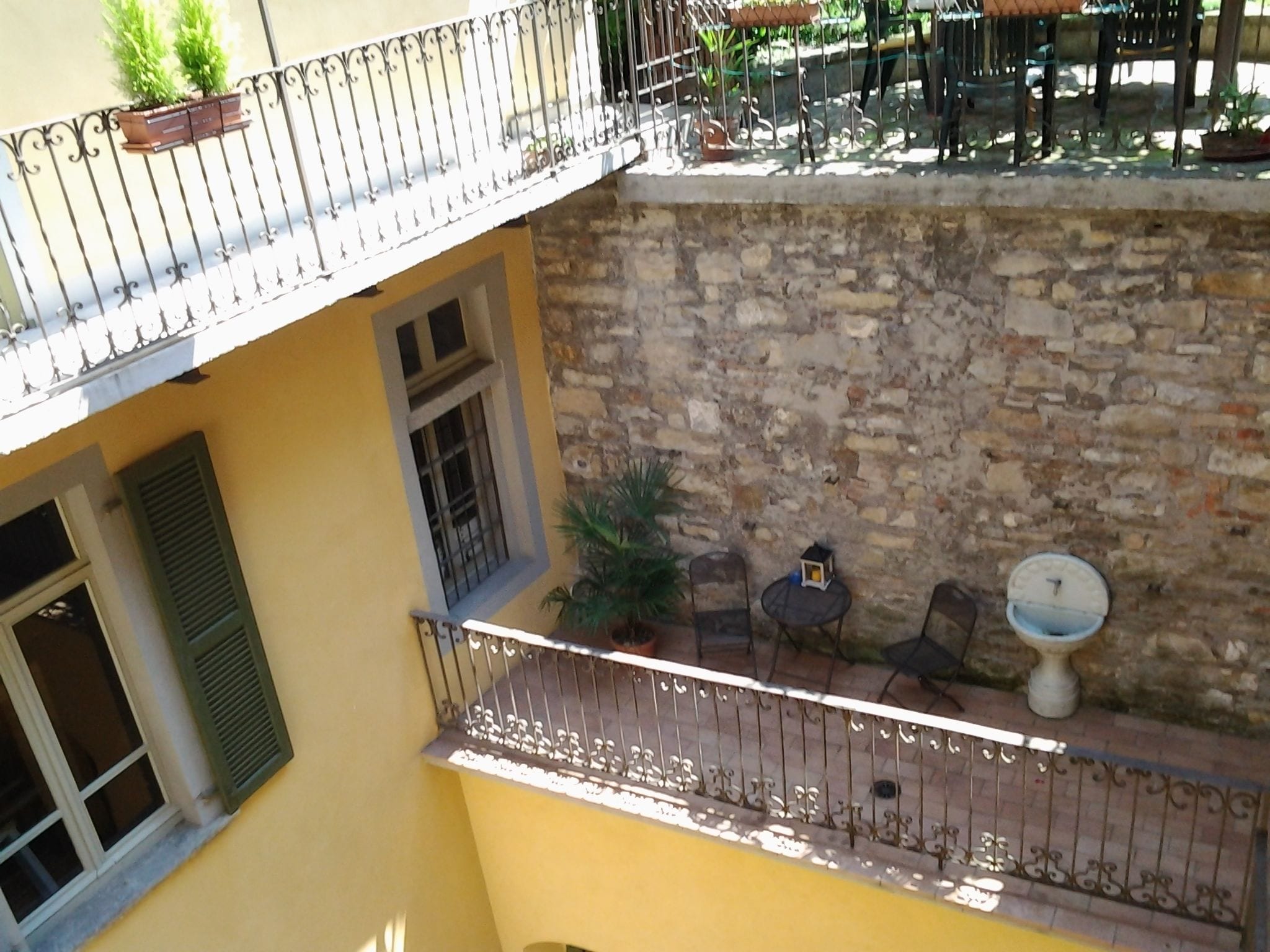 A balcony with a stone wall, a small table with chairs, and a potted plant.