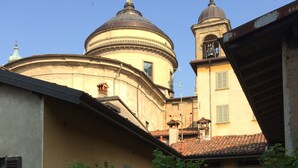 A courtyard with a table set for dining, surrounded by greenery and flowers. - Casa Mario Lupo (Bergamo)