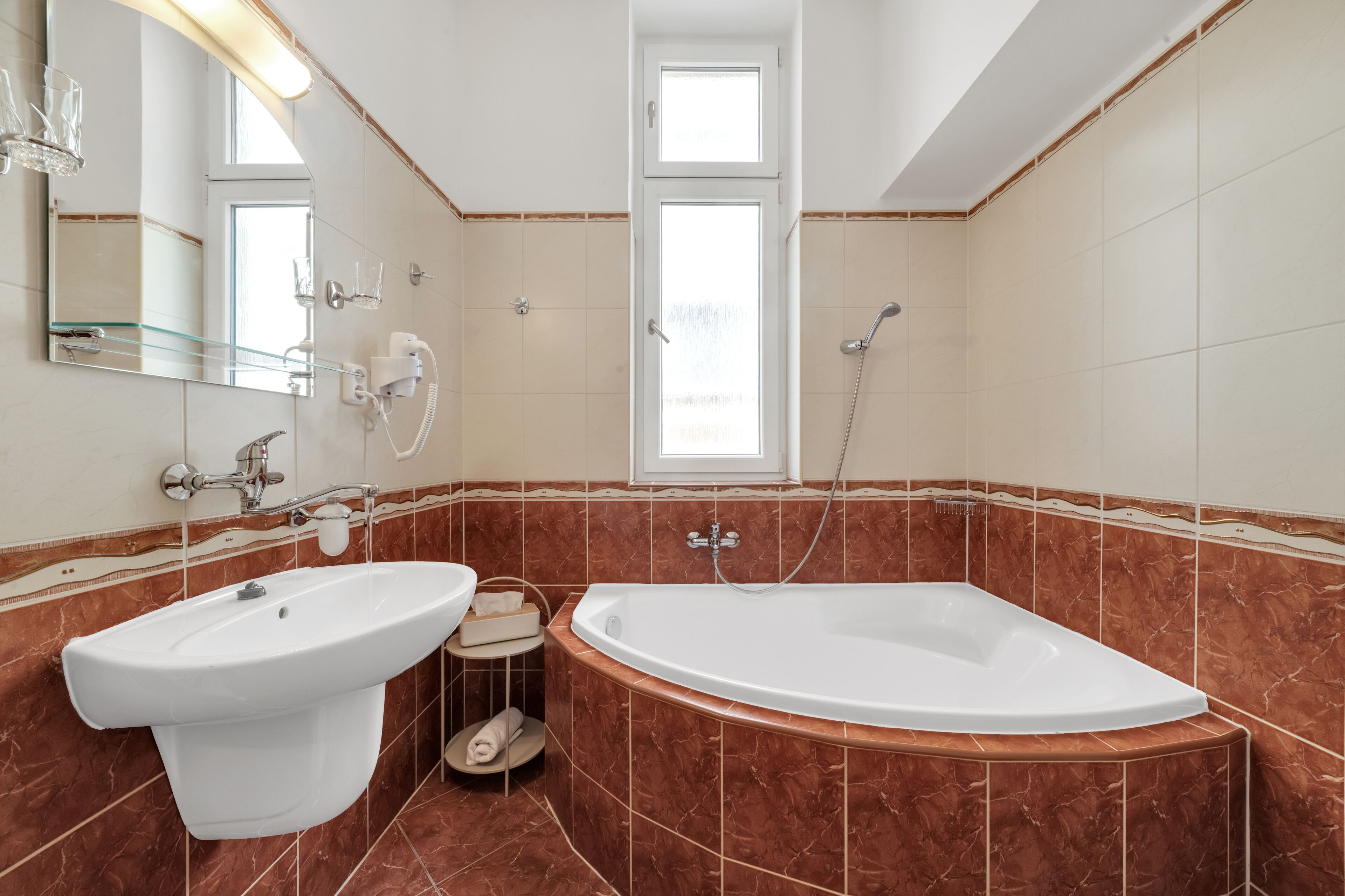 A bathroom with a bathtub, two sinks, a mirror, and a shower.