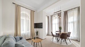 Una sala de estar moderna con un sofá gris, una mesa redonda de madera y un televisor montado en la pared.