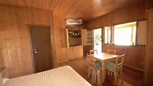A wooden room with a bed, a table with chairs, a kitchen area, and a window. - Garden Village San Marino (Borgo Maggiore)