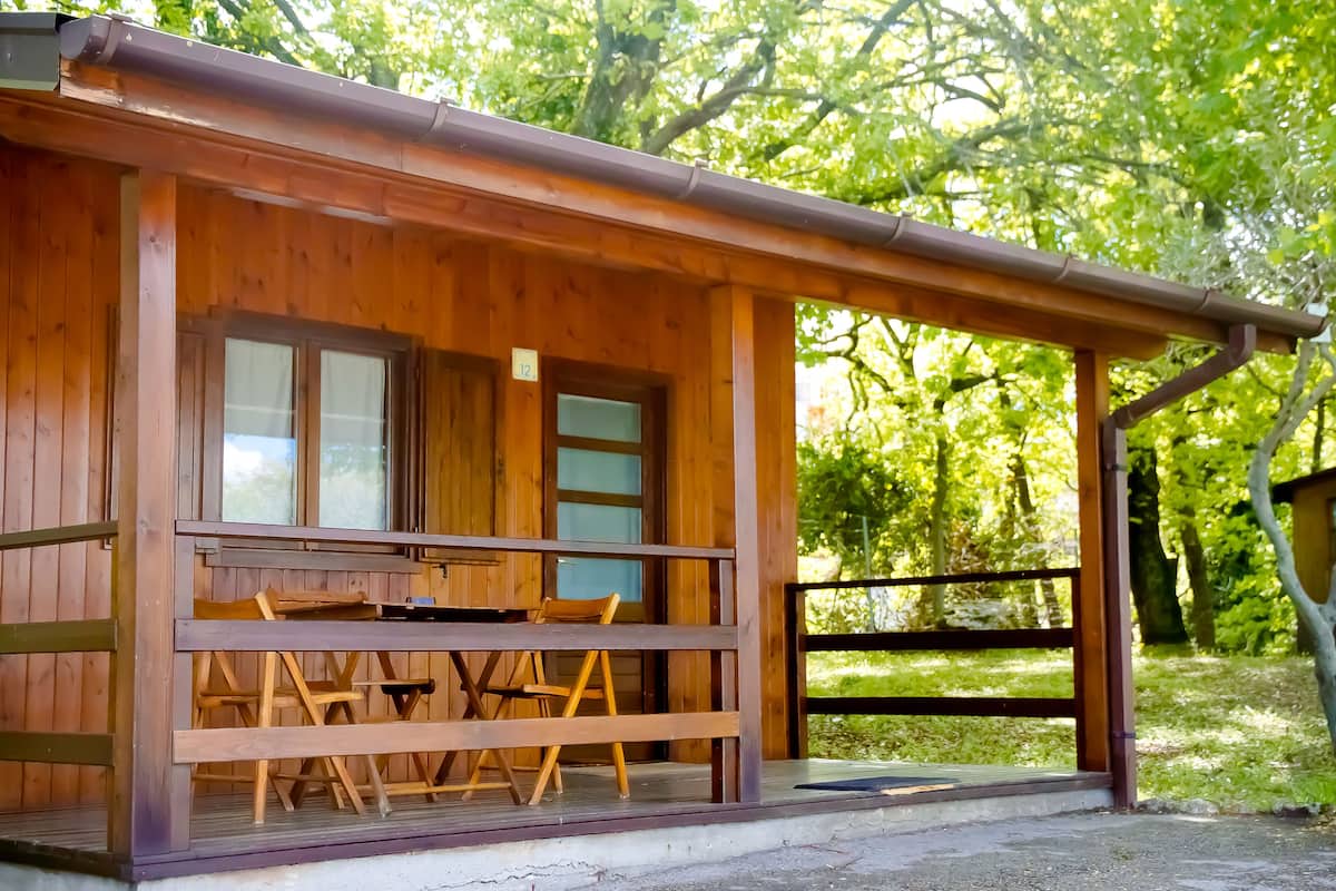 Eine Holzhütte mit Veranda, Tisch und Stühlen.