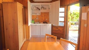 A wooden cabin interior with a dining table, cabinets, and a kitchen area. - Garden Village San Marino (Borgo Maggiore)