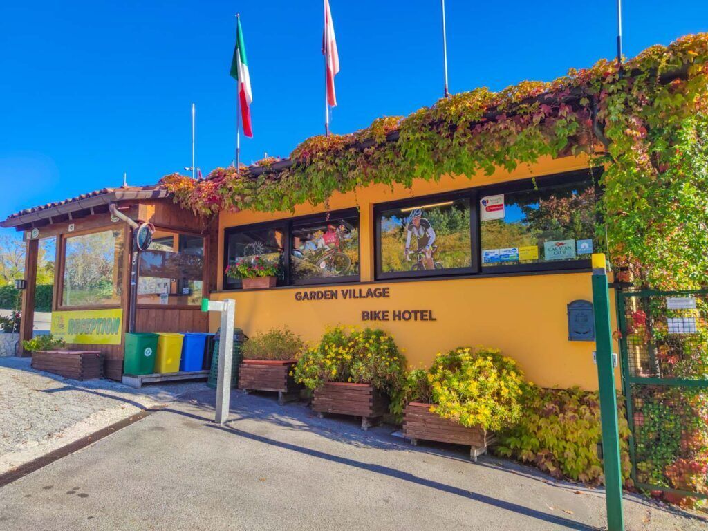 Un hôtel pour cyclistes appelé « Garden Village », doté d’une réception, d’un local à vélos et d’une façade jaune.