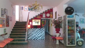 A hotel lobby with a staircase, zebra-patterned reception desk, and a vending machine. - Hotel Villa Elia (Rimini)