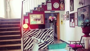 A hotel lobby with a zebra-striped reception desk, a vintage scooter, and a staircase. - Hotel Villa Elia (Rimini)