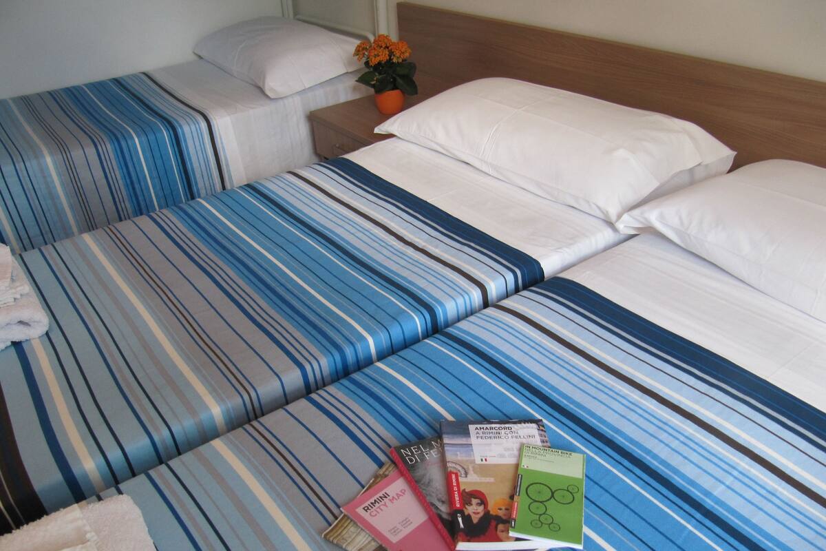 A hotel room with two beds, each with striped bedding. There are books and a map on the beds.