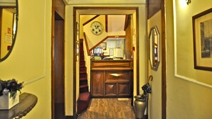 A hallway with a wooden staircase, a clock, and a desk with a mirror. - Hotel Vecchia Milano (Milan)