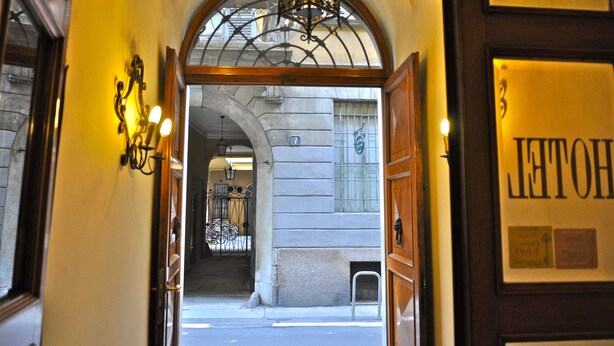 An entrance to a hotel with a wrought iron gate, a chandelier, and a sign with the hotel's name. - Hotel Vecchia Milano (Milan)