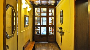 A hallway with wooden doors, a bench, and wall-mounted lights. - Hotel Vecchia Milano (Milan)