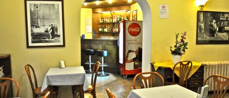 A restaurant interior with tables, chairs, a bar area, and a Coca-Cola refrigerator.