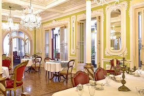 A dining area with ornate chandeliers, red upholstered chairs, and white tablecloths. - Palacete Chafariz D'El Rei by Unlock Hotels (Lisbon)