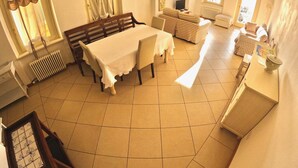 Un coin repas avec une table dressée pour quatre personnes, un banc et un canapé.