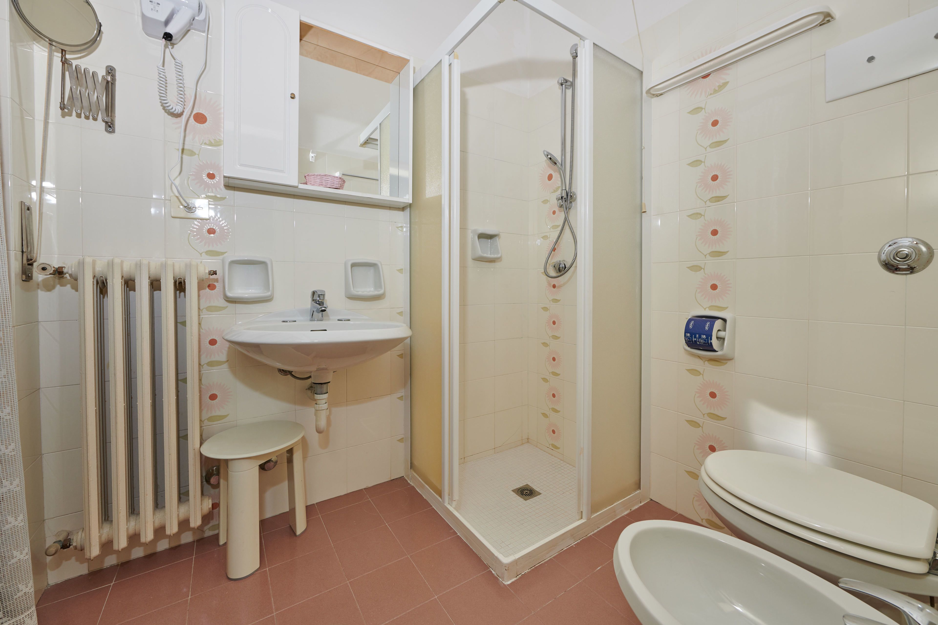 Een badkamer met douche, wastafel, toilet en spiegel.