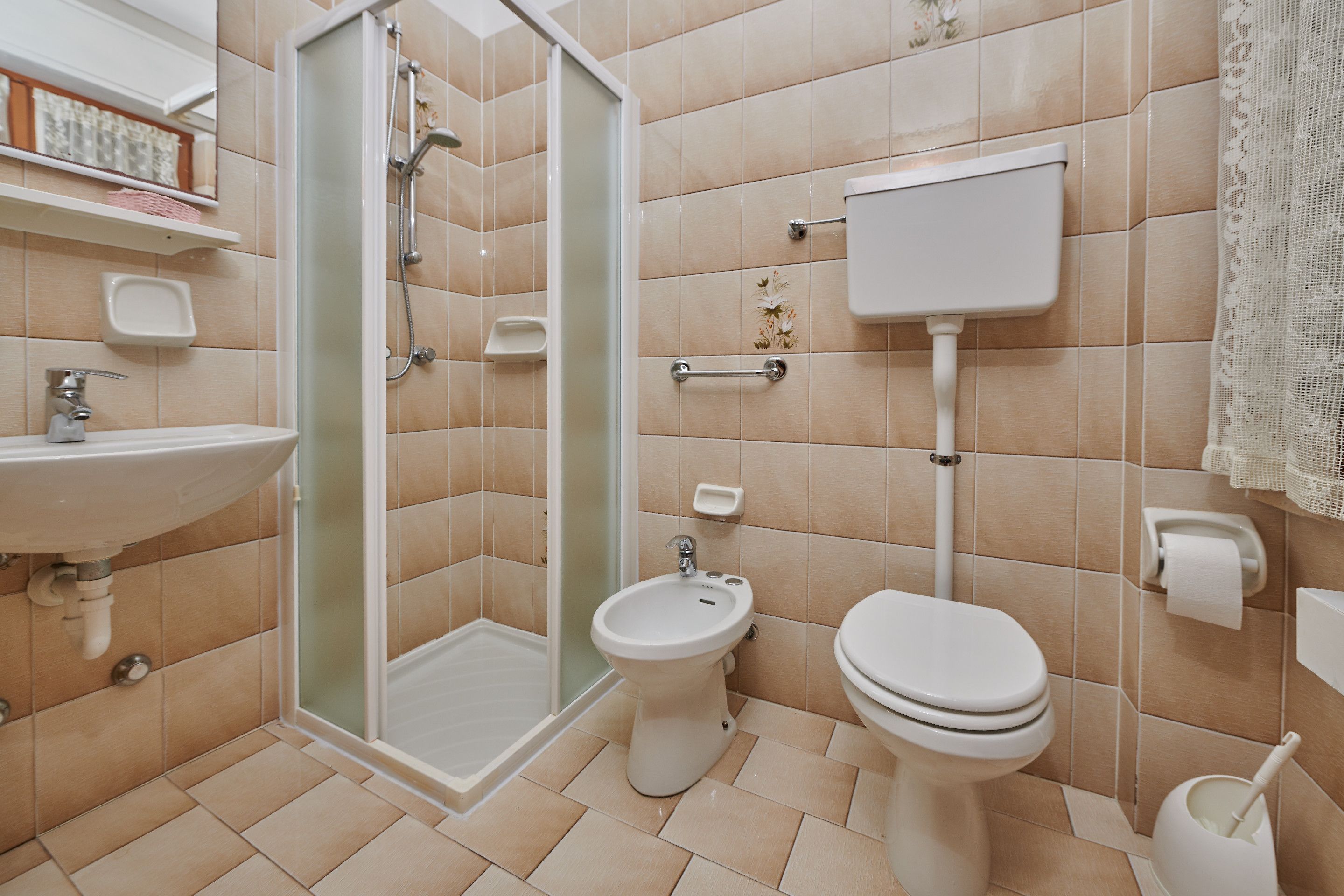 Un baño con ducha, inodoro, bidé y lavamanos.