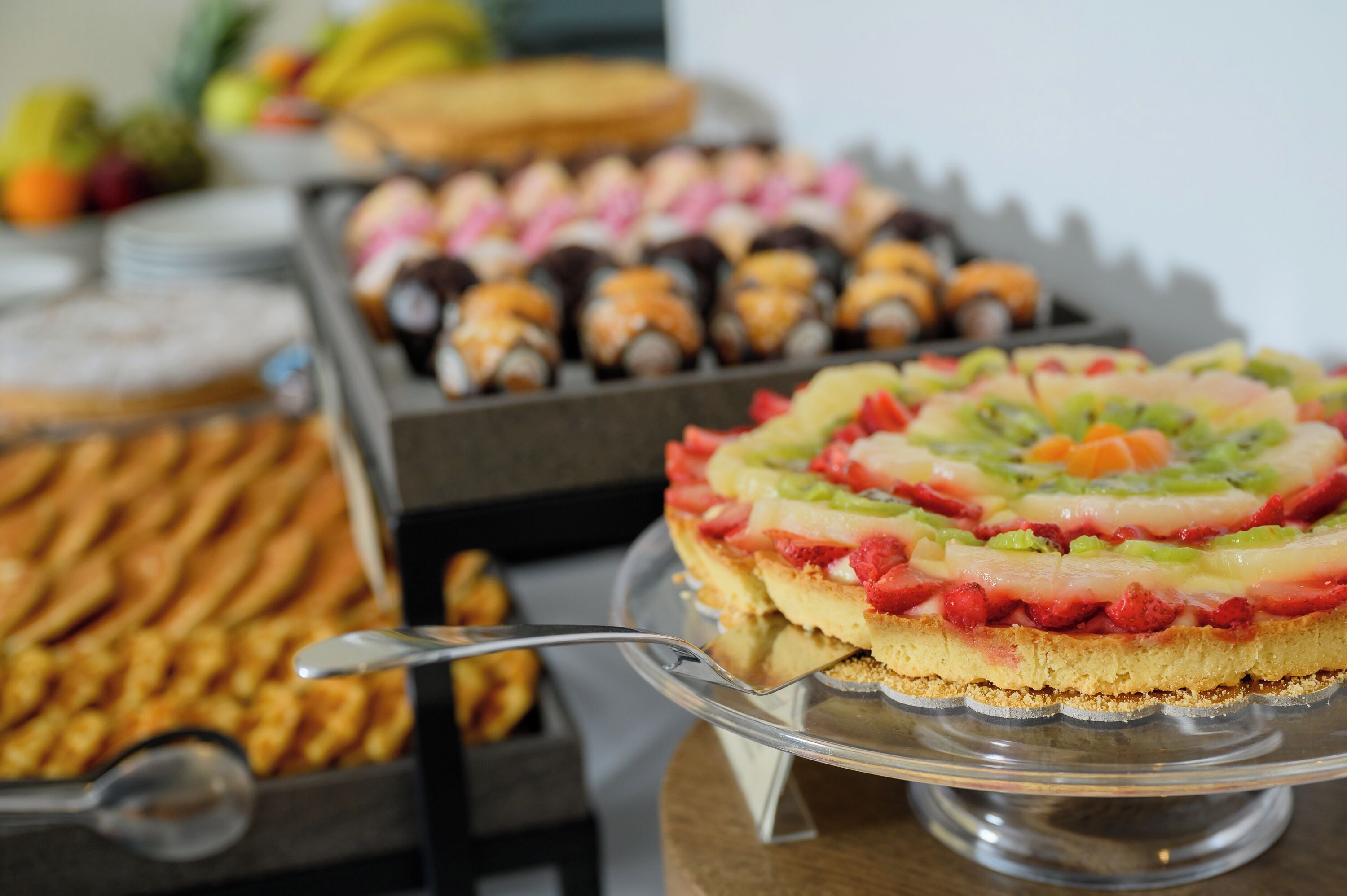 A buffet with various desserts including a layered fruit tart, pastries, and other baked goods.