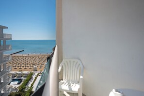 Ein Balkon mit Blick auf einen Strand, Liegestühle und einen Pool.