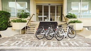 L’entrée d’un immeuble, avec un sol carrelé, un escalier et trois vélos garés devant.