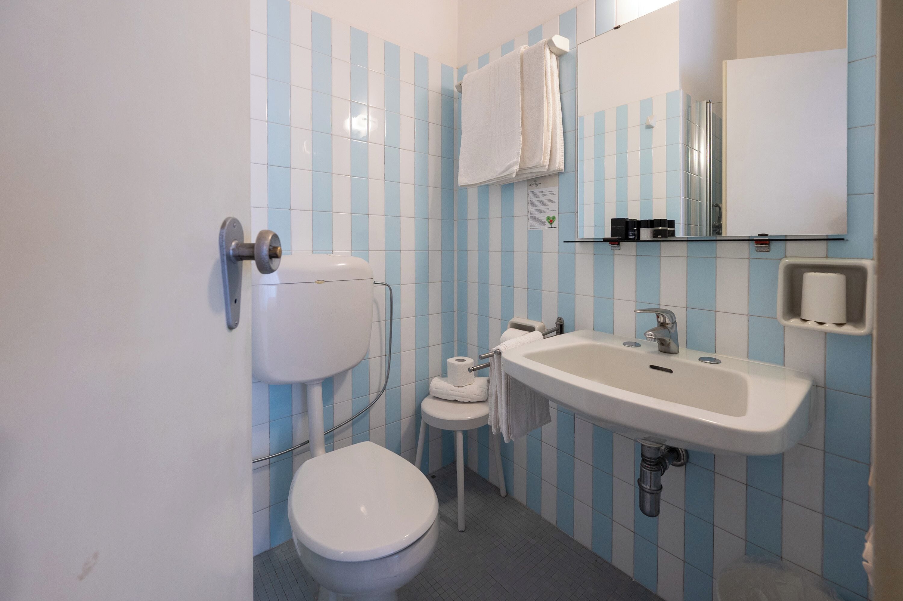 A bathroom with a toilet, sink, and towel rack.