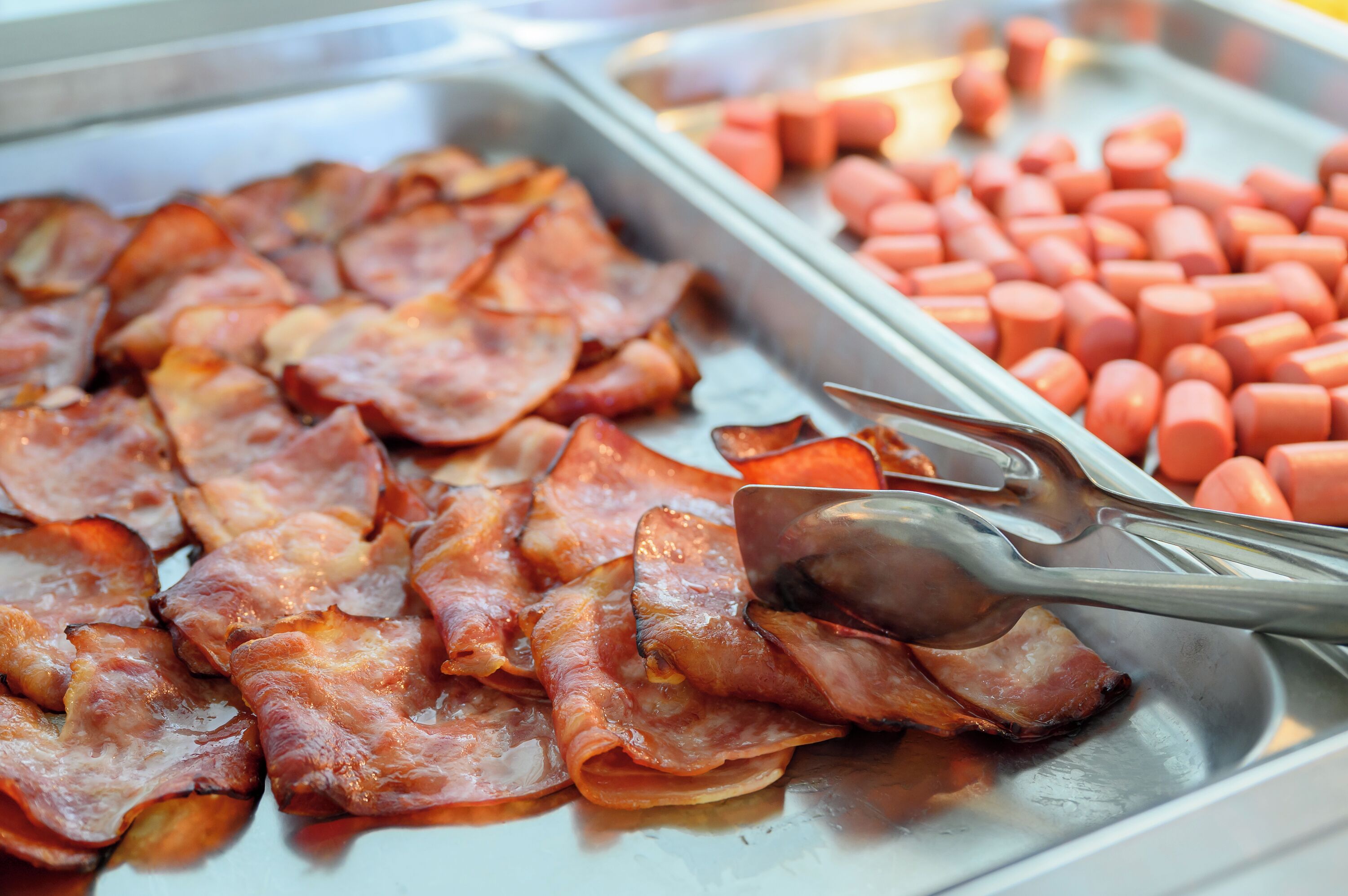 Ein Frühstücksbuffet mit Speck und Hot Dogs.