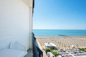 Un balcon donnant sur une plage oĂč lâon peut voir des rangĂ©es de transats et de parasols.