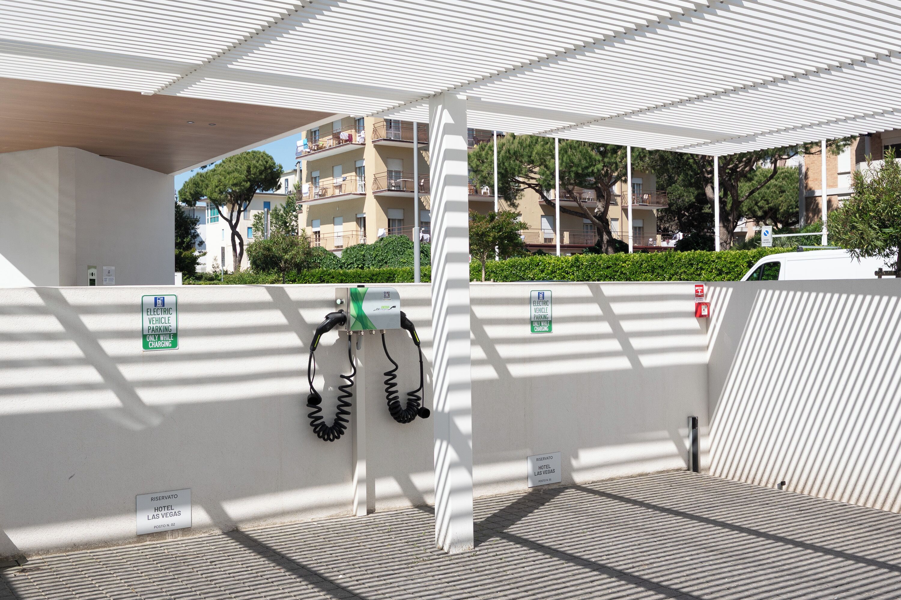 A covered outdoor area with a parking sign, a charging station, and a hotel sign.