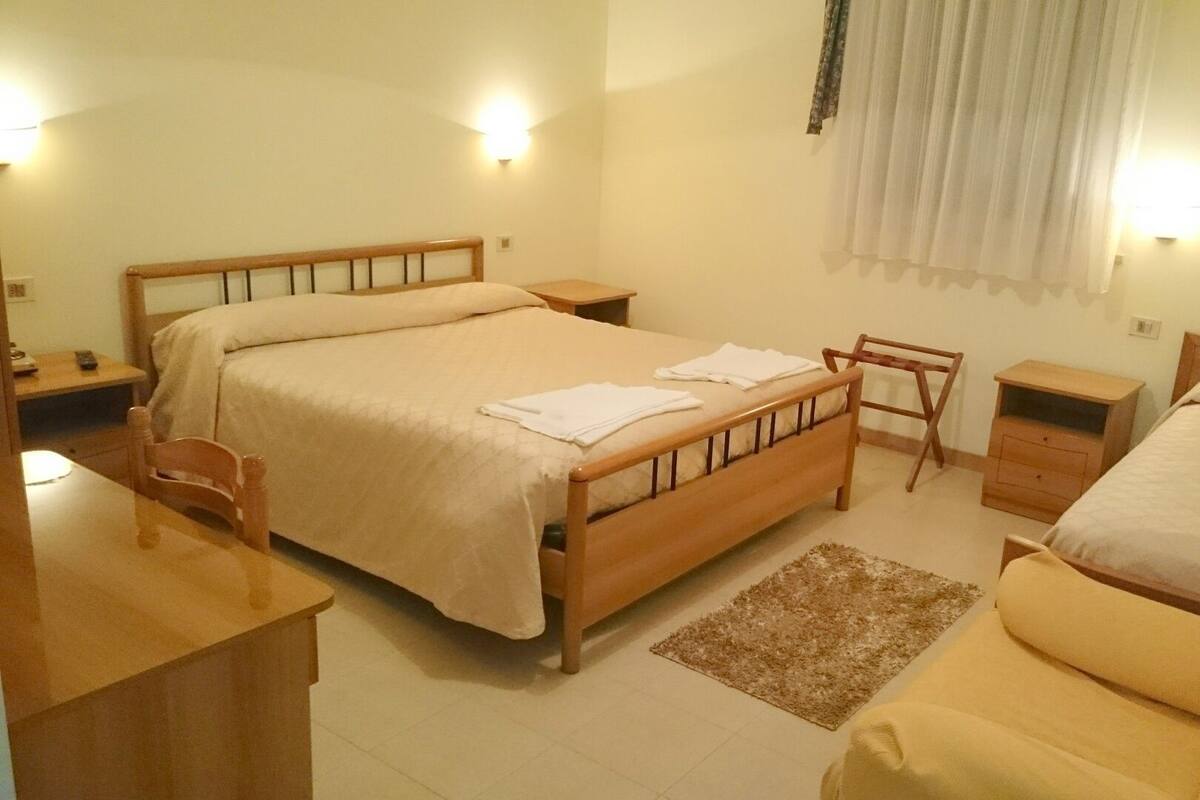 Habitación de hotel con cama doble, escritorio, silla, mesita y mesita de noche.