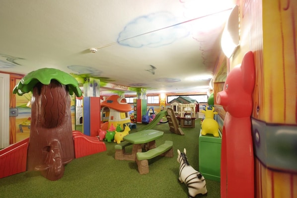 Un espace de jeux pour enfants comprenant diverses structures ludiques, notamment un toboggan, un mur d’escalade et une maison de jeu.