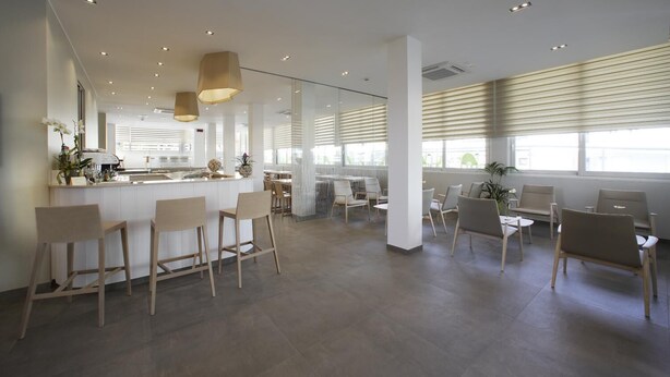 A modern interior with a bar area, seating, and large windows. - Hotel Gardenia (Jesolo)