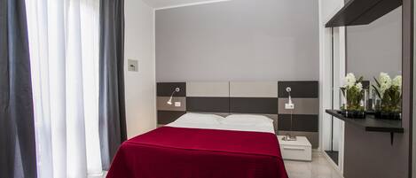 Un dormitorio moderno con una cama grande, mesitas de noche y un espejo.