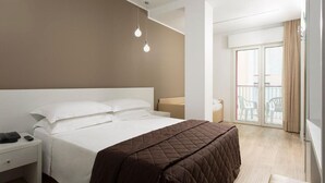 A hotel room with a large bed, a bedside table with a phone, and a balcony with chairs. - Hotel Gardenia (Jesolo)