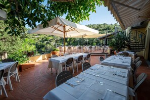 Un'area pranzo all'aperto con tavoli e sedie, immersa nel verde e con vista panoramica.