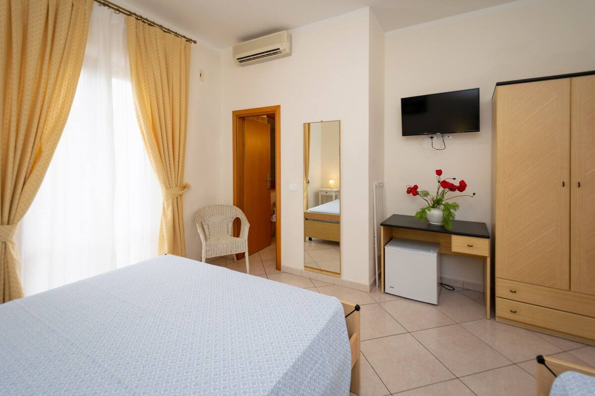 A hotel room with a bed, a desk, a television, and a wardrobe.