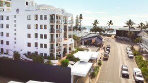 Un hôtel à plusieurs étages doté de balcons, d’un espace extérieur couvert et offrant une vue sur la plage.